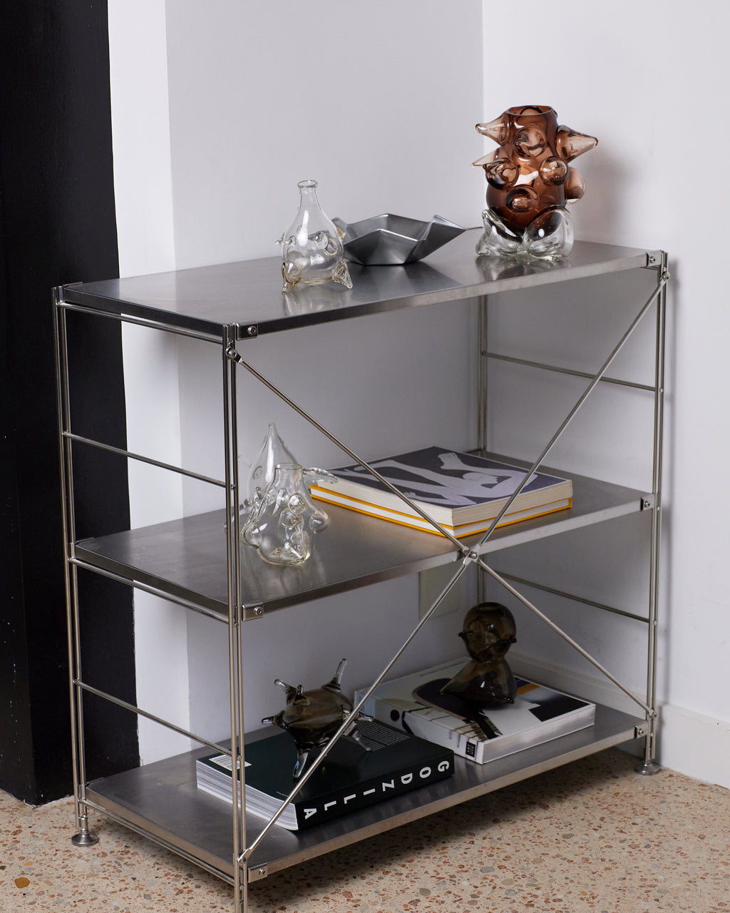 Metal shelving unit with decorative items against a white wall