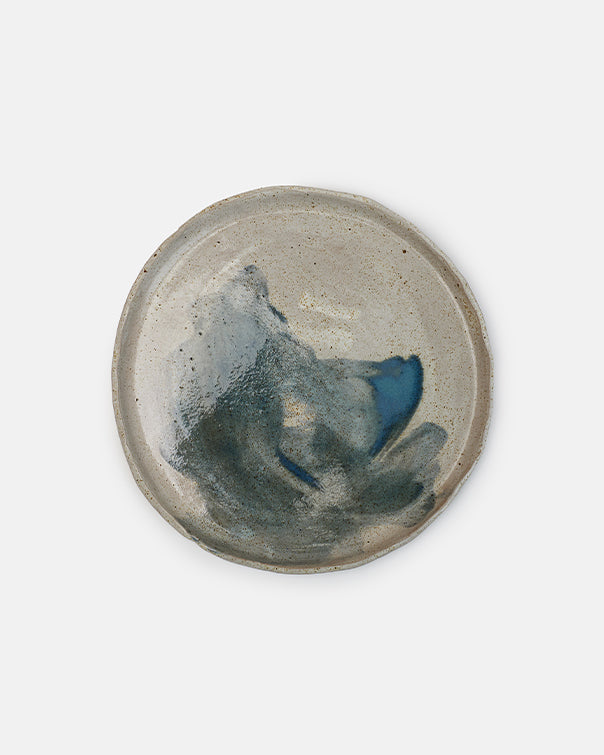 Ceramic dish with a textured surface and blue accent on a white background