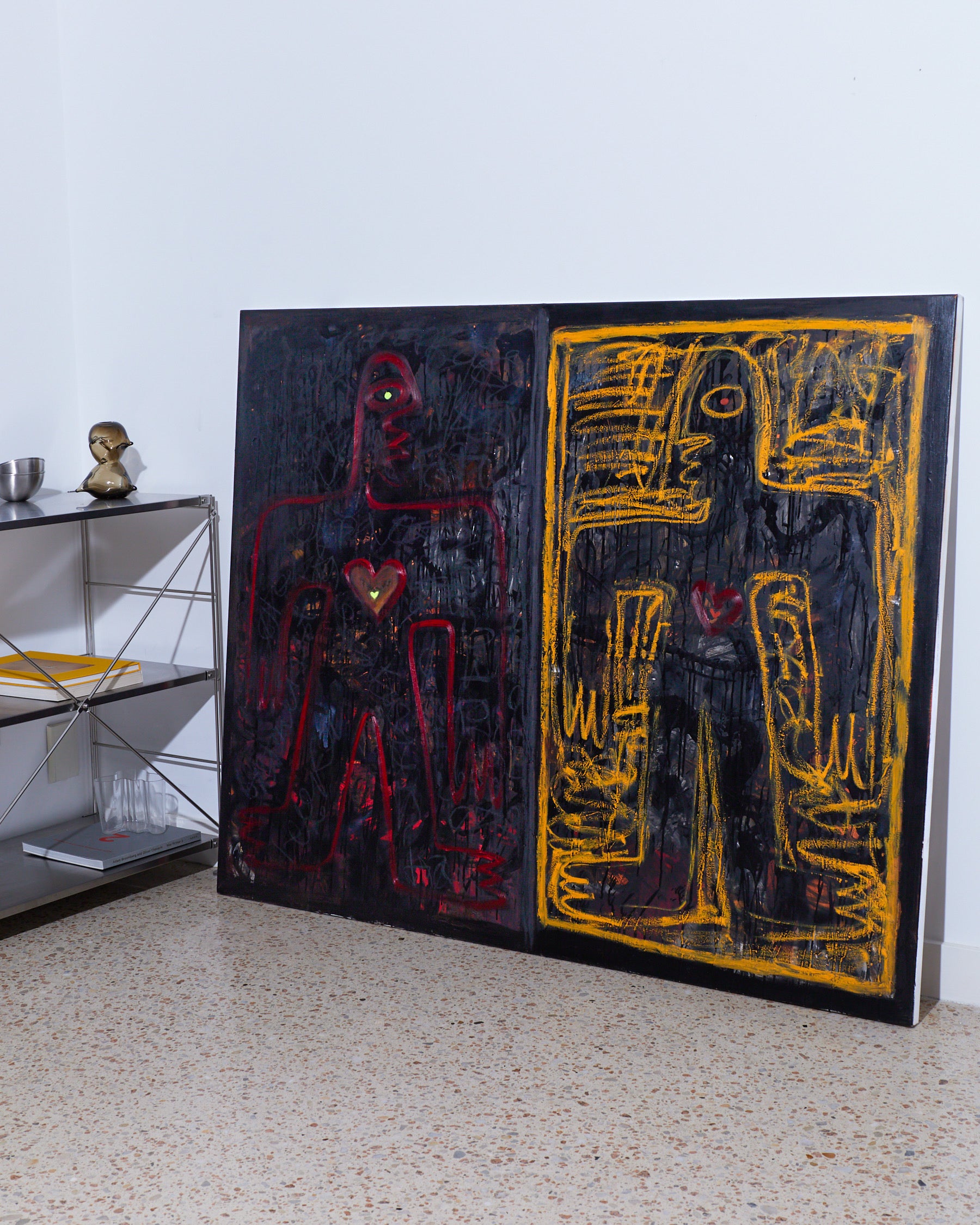 Abstract artwork with black, red, and yellow colors on a white wall.