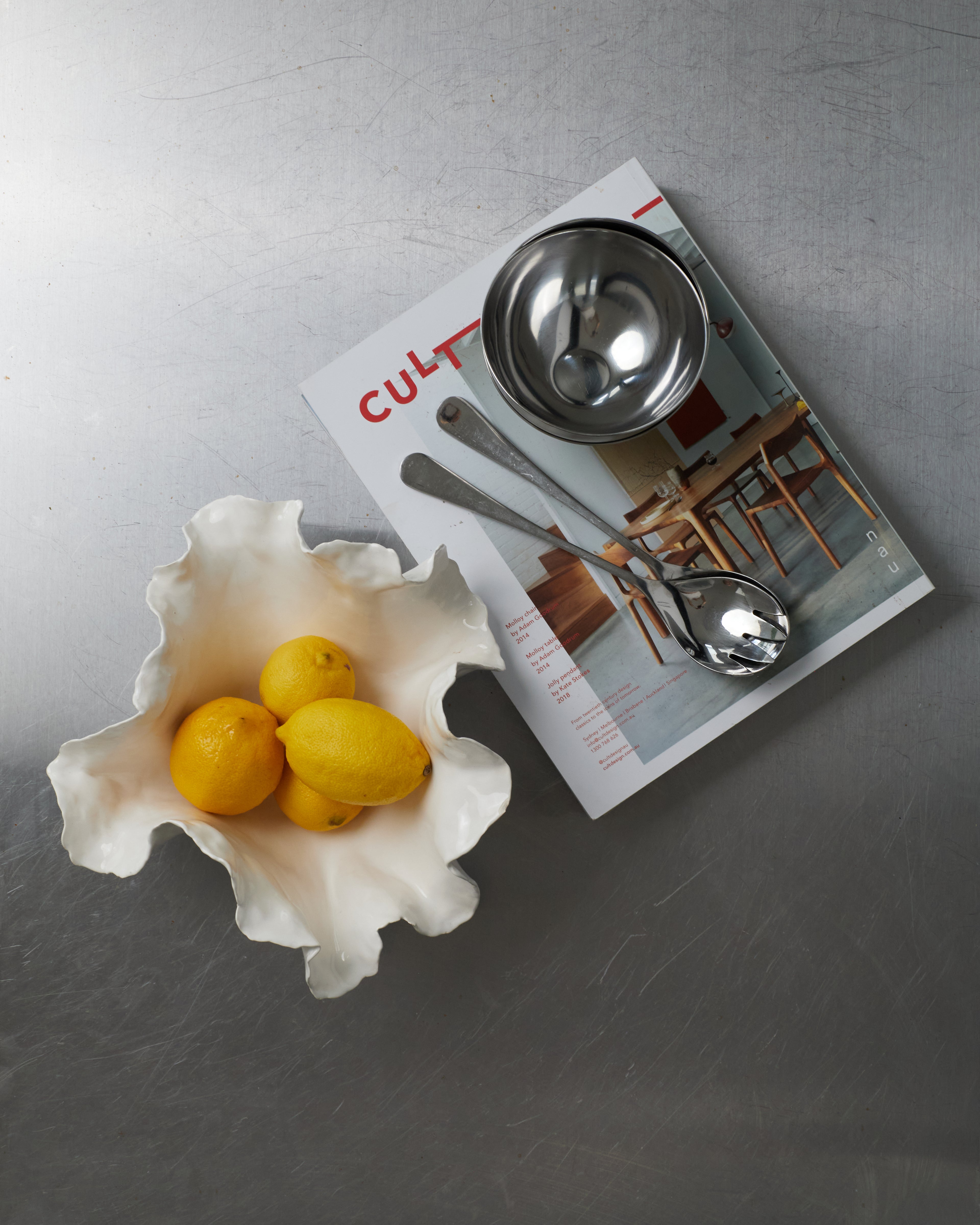 White shell-shaped bowl with lemons on a magazine with kitchen-themed layout