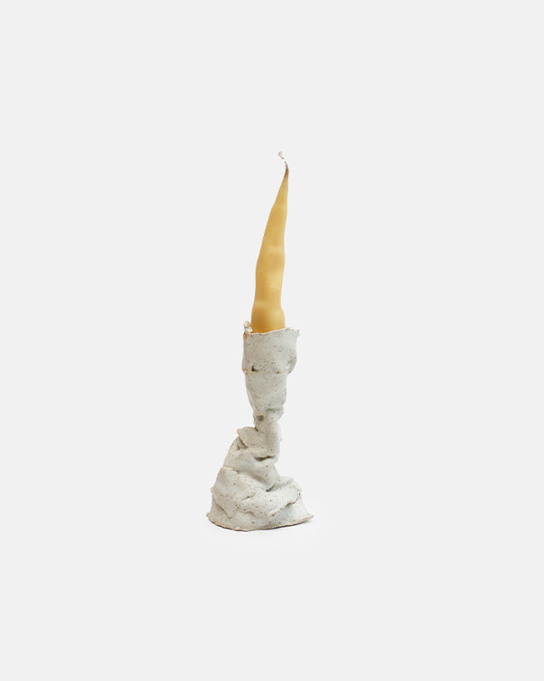 Candle in a textured stone holder on a white background