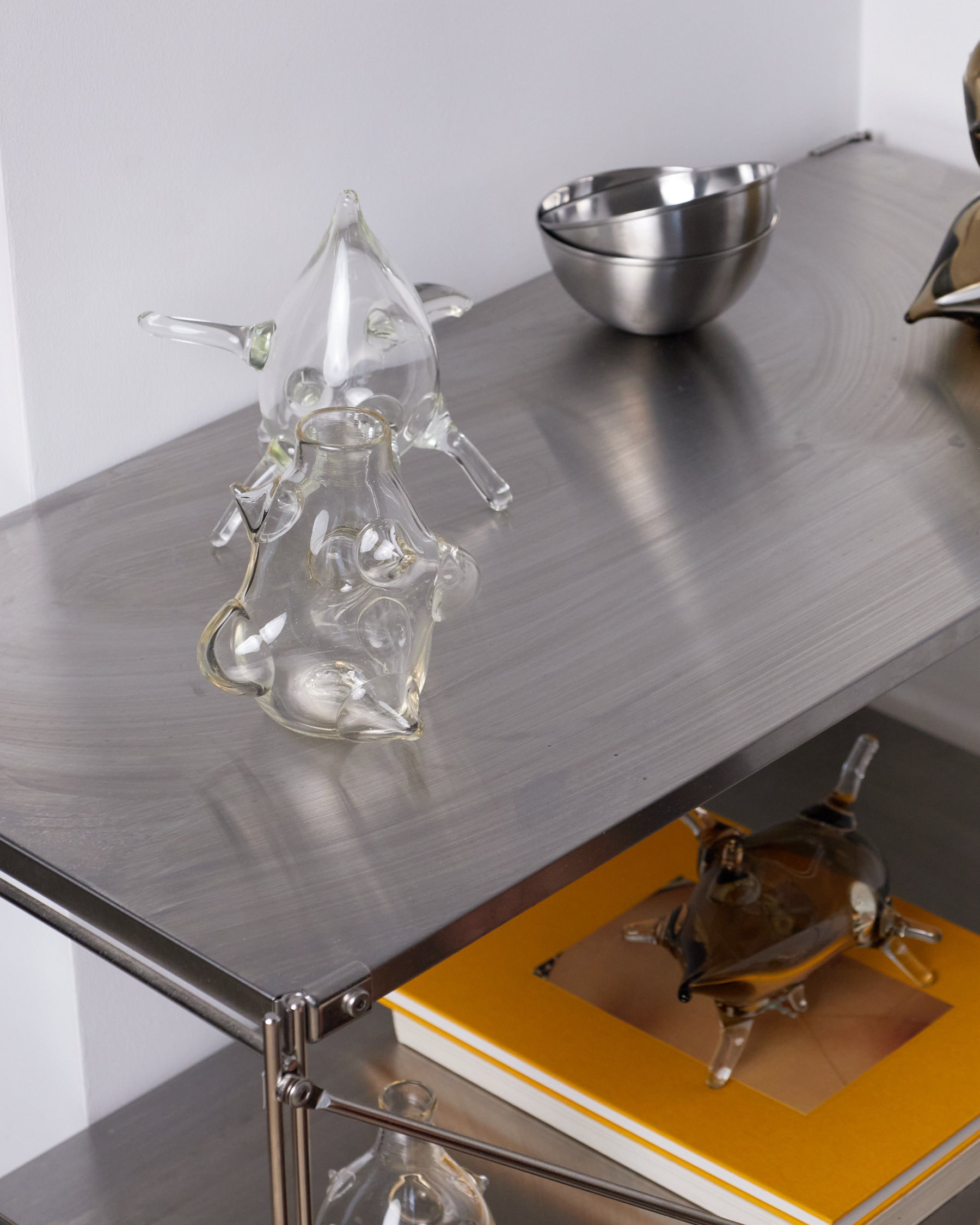 Metallic surface with decorative items including a glass sculpture and metal bowl.