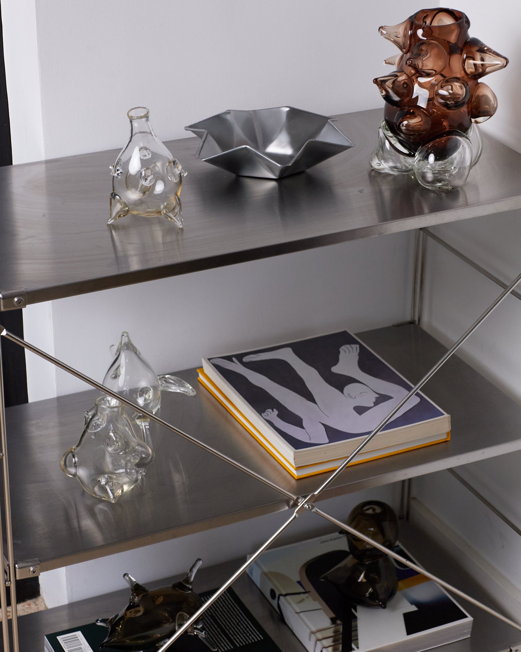 Metal shelf with decorative items including glass sculptures and a book.