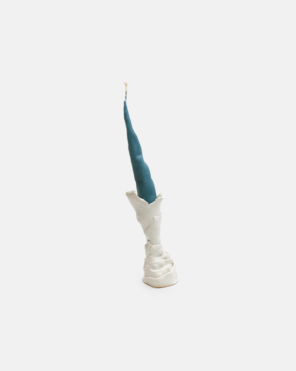 Blue candle in a white ceramic holder on a light beige background
