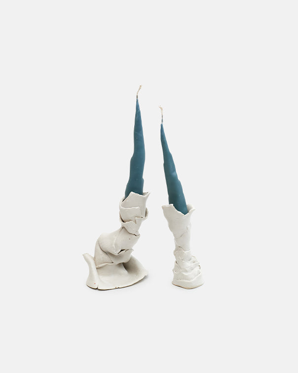 White ceramic boot-shaped candle holders with blue candles on a white background