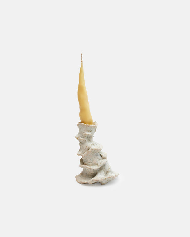Candle in a textured ceramic holder on a white background