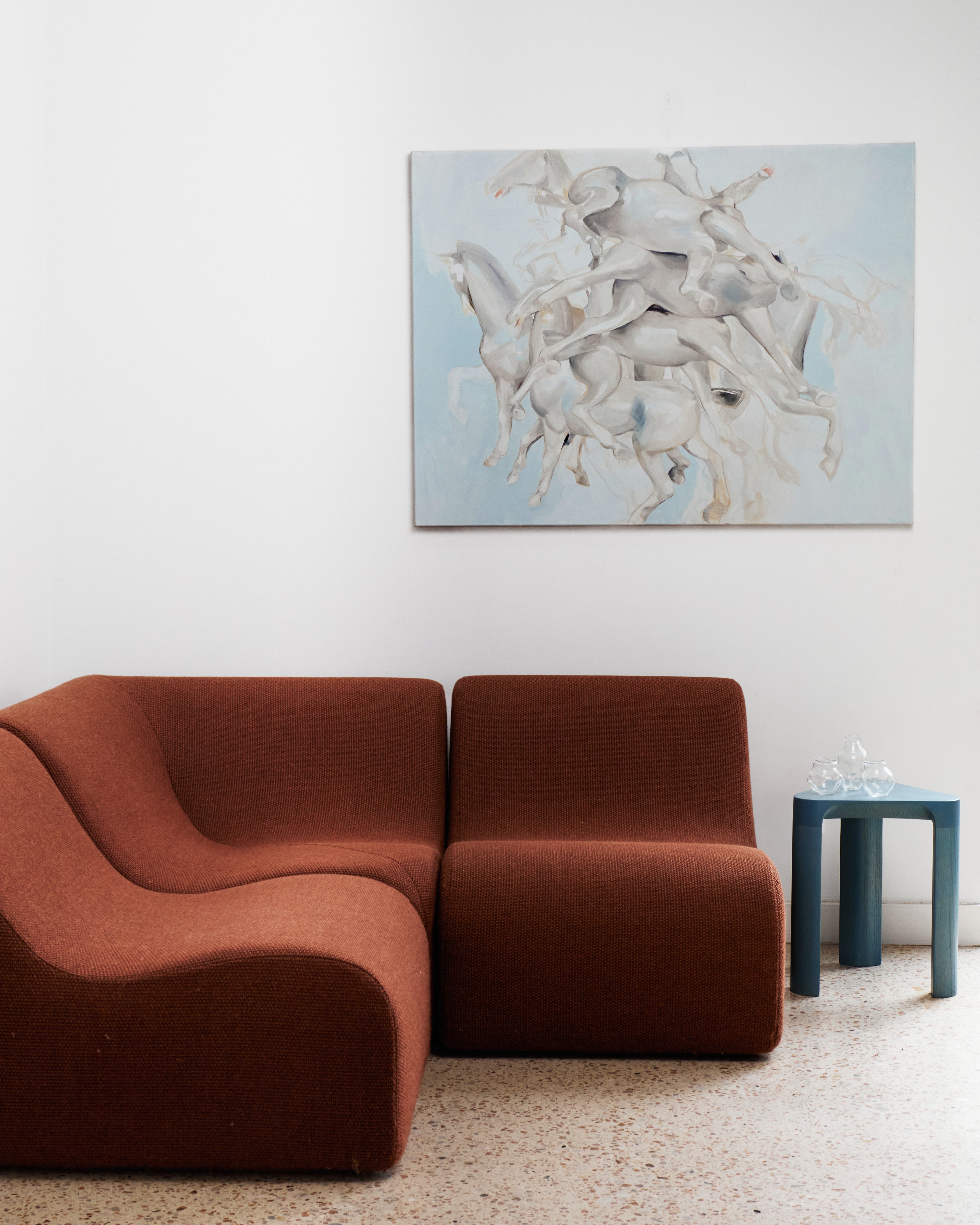 Modern brown sofa in a room with a large abstract painting on the wall.