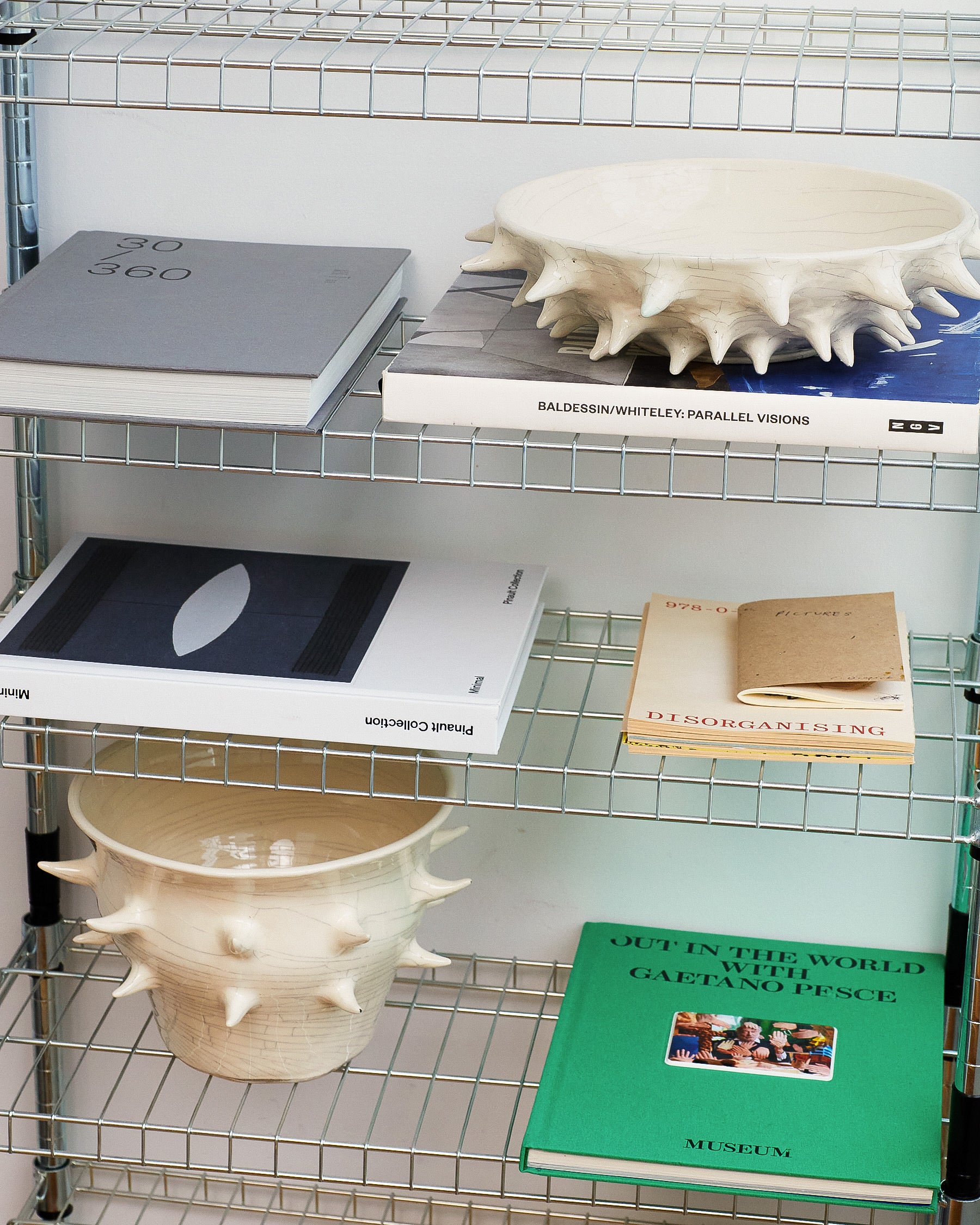 Shelving unit with books and ceramic items on a grid-patterned wall.