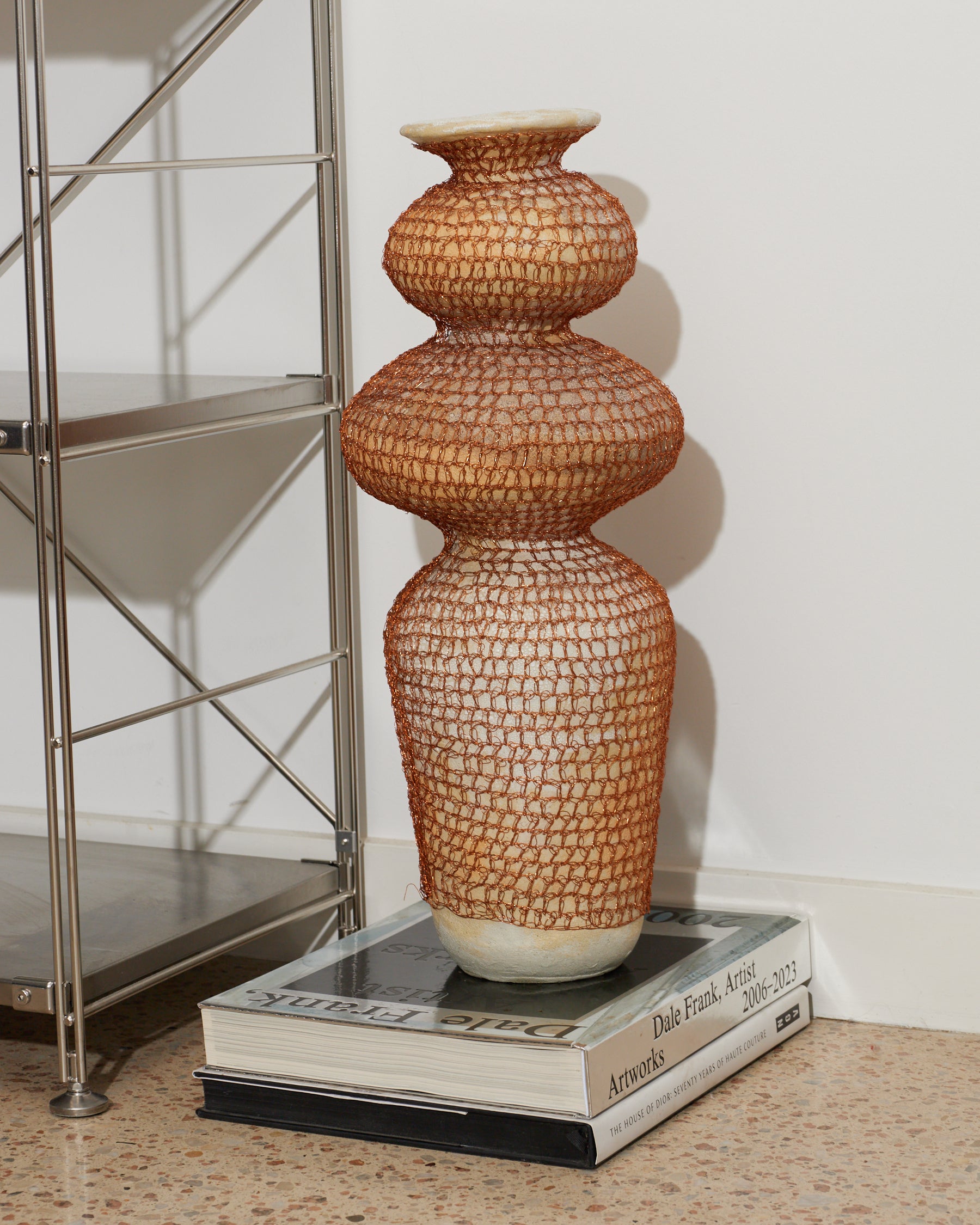 Decorative vase on a book with a metal shelf in the background
