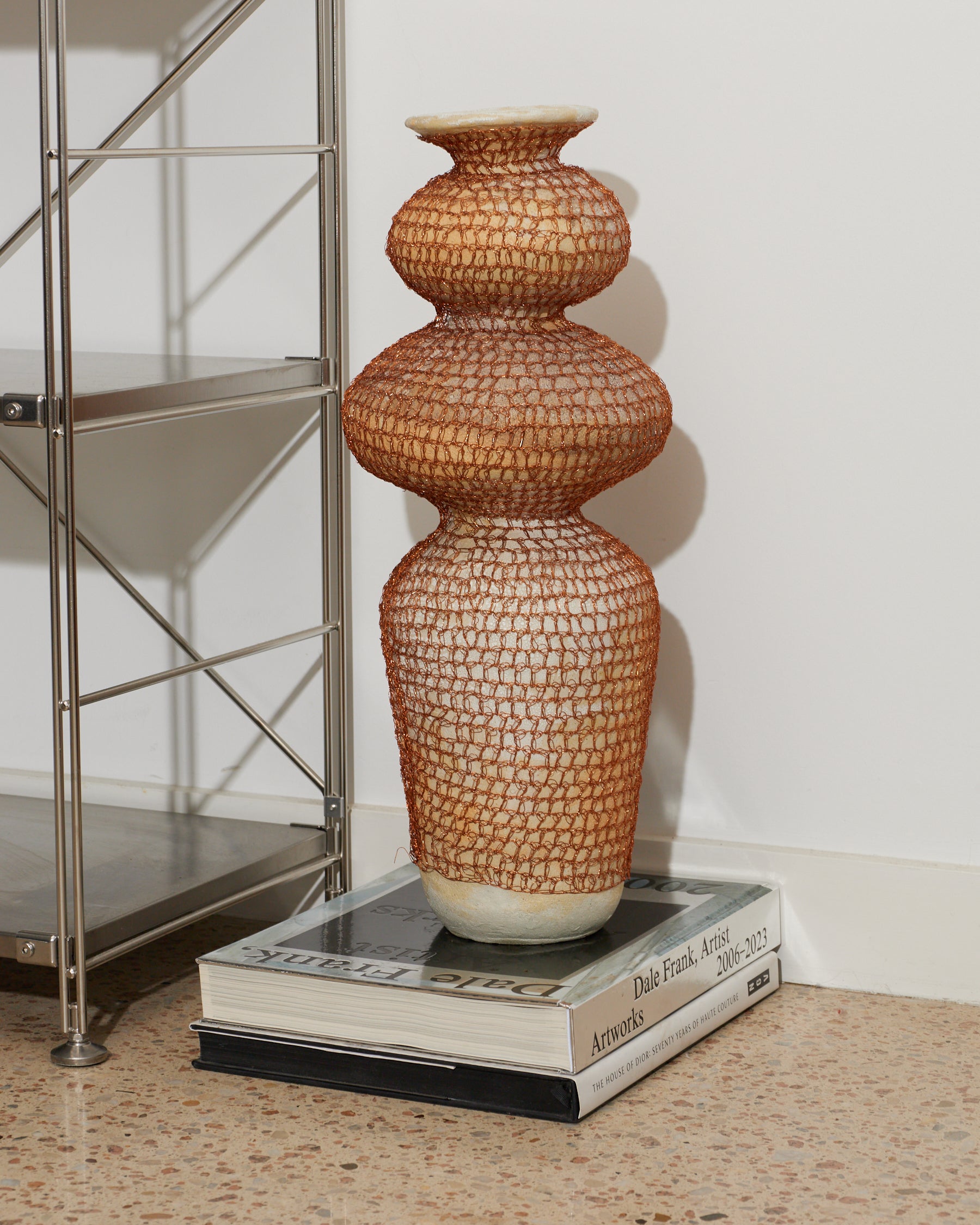 Decorative vase on a book with a metal shelf in the background