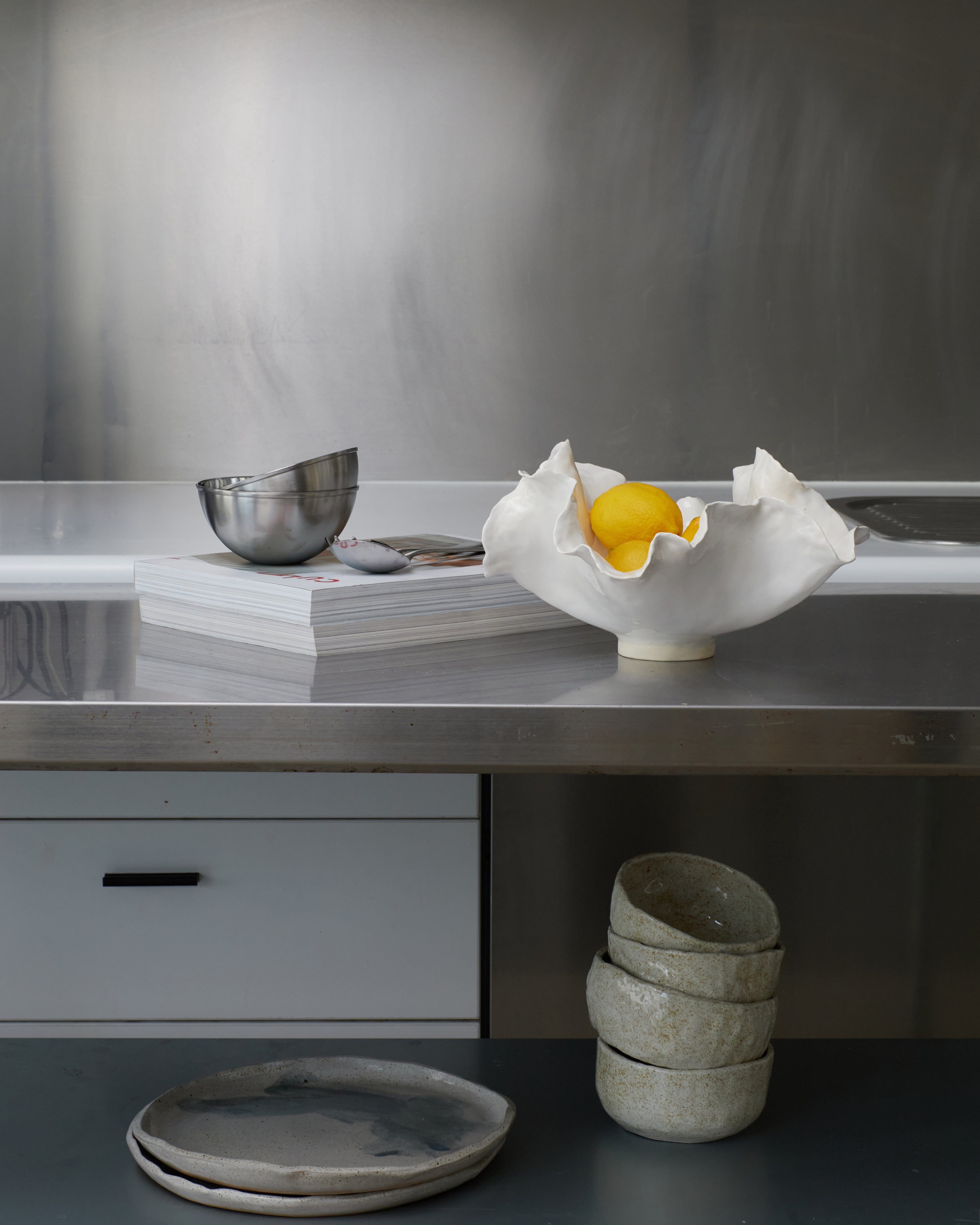 Kitchen counter with ceramic bowls and a lemon on a metallic surface.