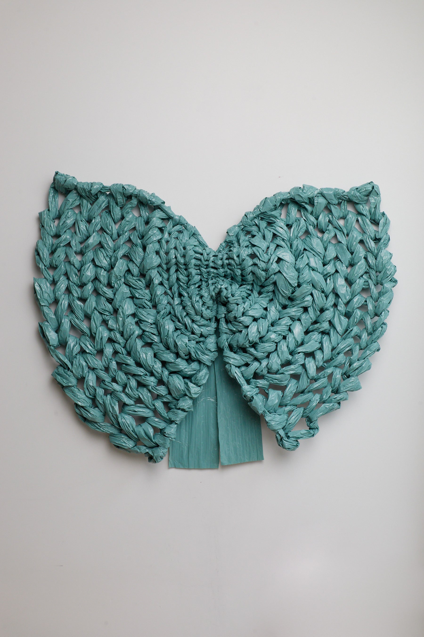 Teal knitted bow on a light gray background