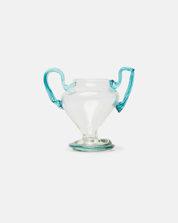 Clear glass vase with blue handles on a light gray background