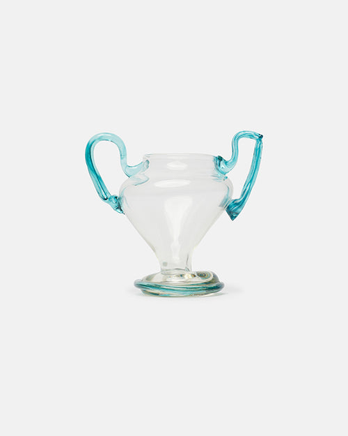Clear glass vase with blue handles on a light gray background