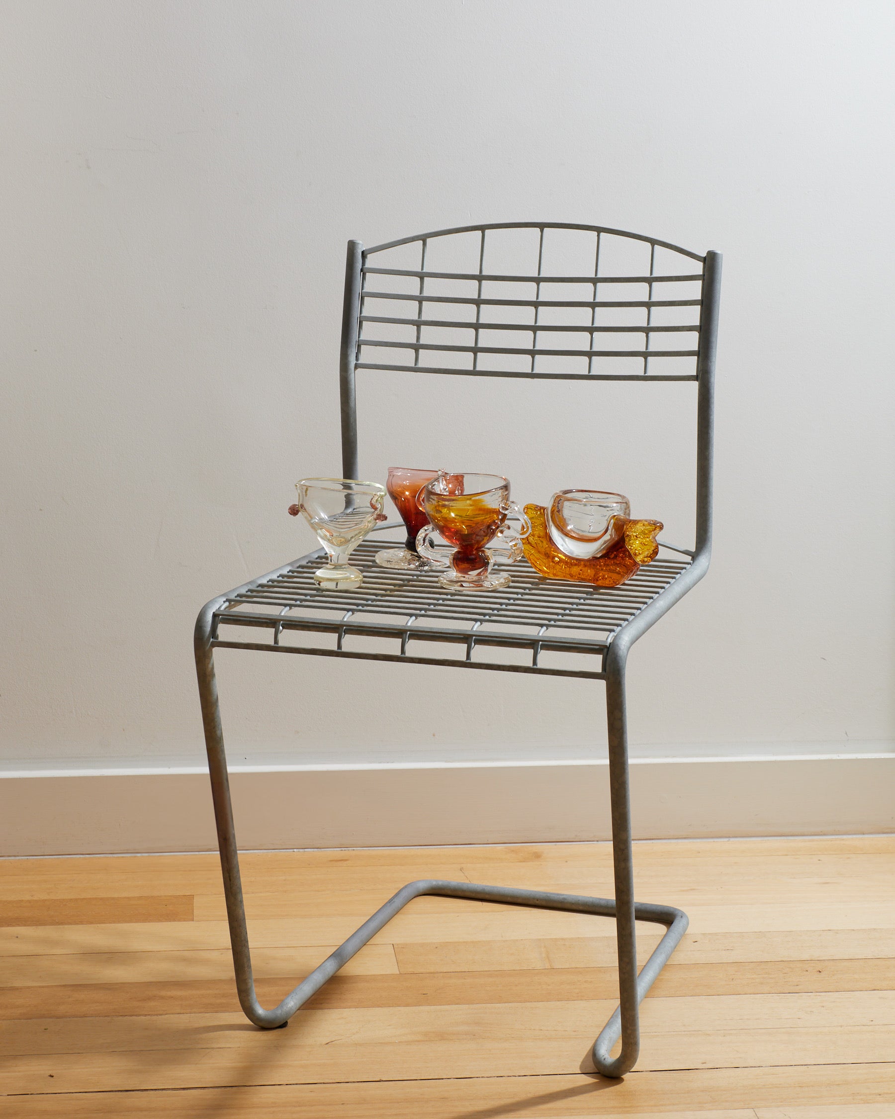 Metal chair with a small table on a wooden floor against a plain wall