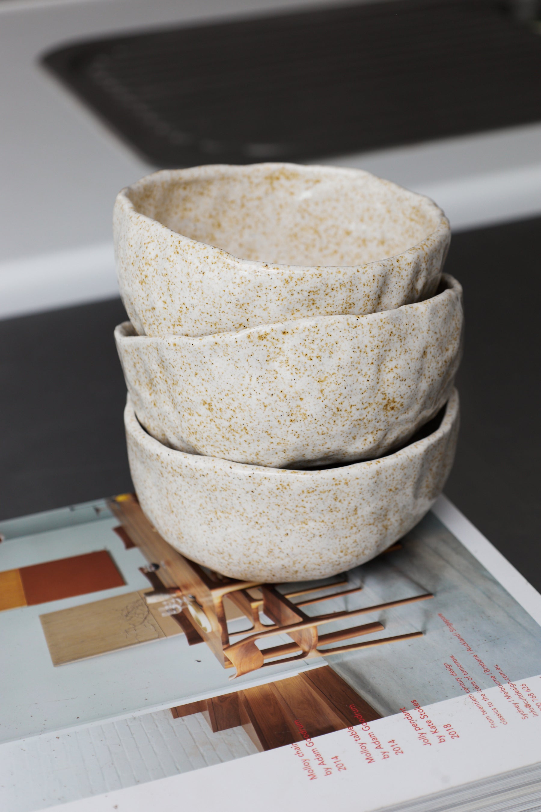 Stack of three ceramic bowls on a magazine with a blurred background