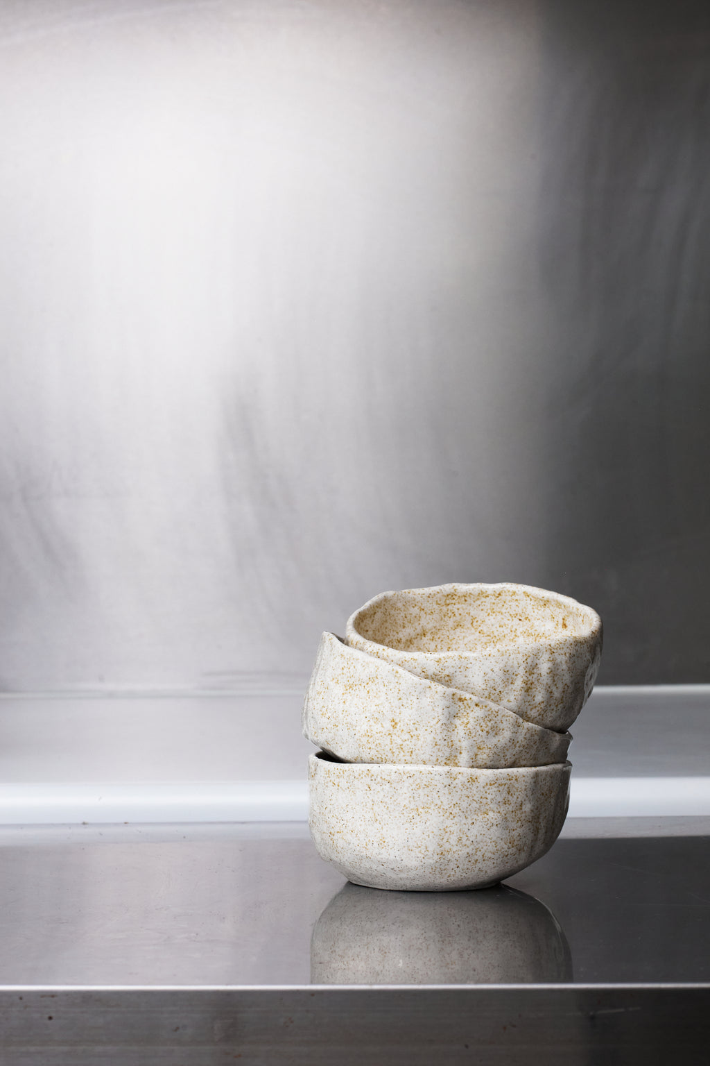 Stack of three ceramic bowls on a reflective surface with a neutral background