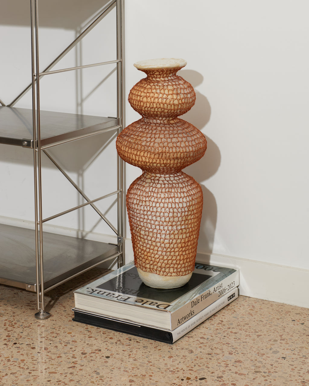 Decorative vase on a book with a metal shelf in the background