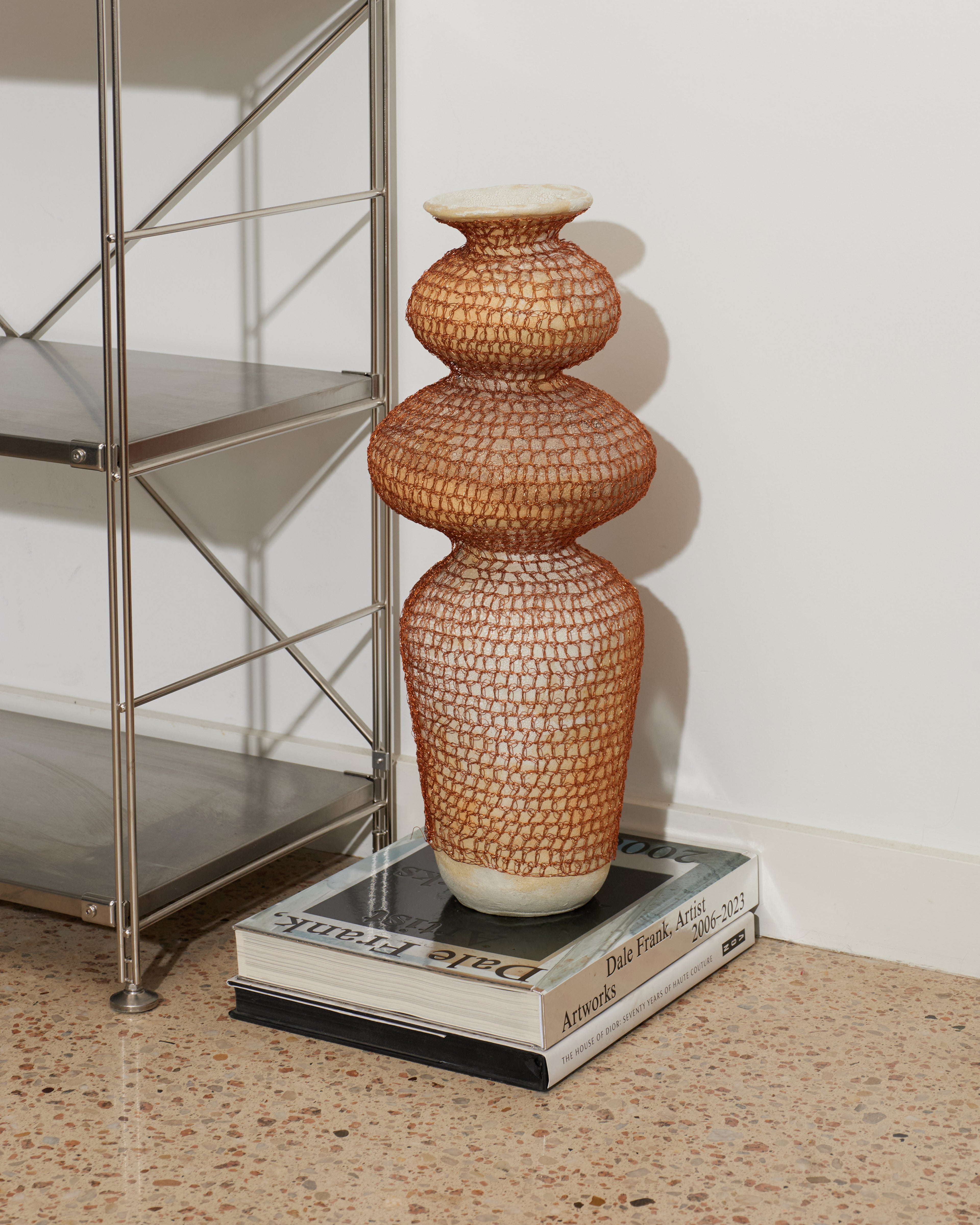 Decorative vase on a book with a metal shelf in the background